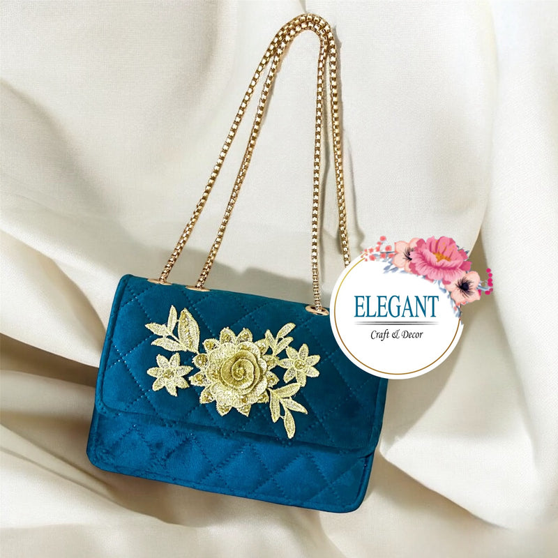 An elegant, quilted emerald color velvet shoulder bag featuring a striking gold floral embroidery and a matching dual-chain strap.