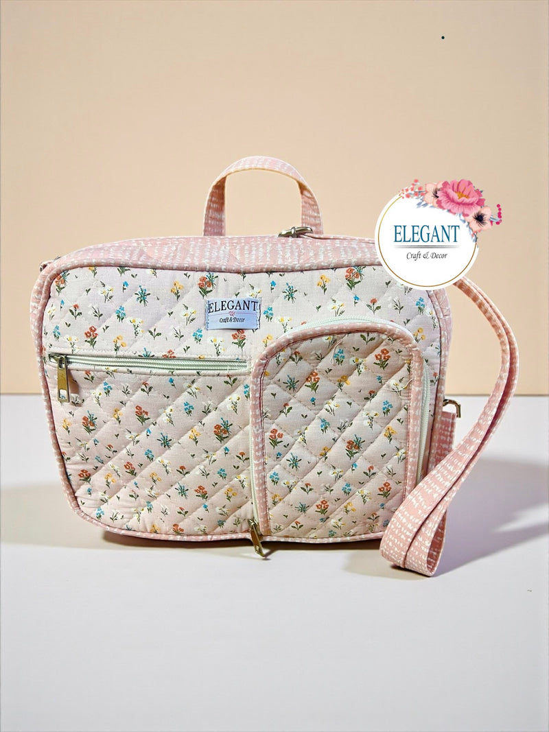 A stylish pink and grey quilted bag featuring multiple zip pockets and a versatile shoulder strap.