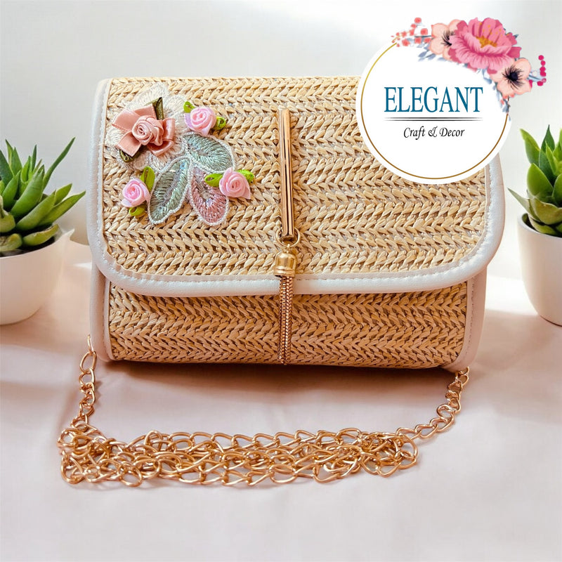 A classy handwoven straw clutch with soft neutral tones, adorned with delicate floral embroidery and a sleek gold clasp—perfect for a chic, minimal yet elegant look.