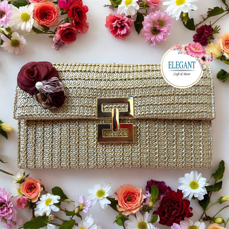 A classy woven clutch in a warm golden tone, featuring a textured finish, elegant metal clasp, and a delicate 3d floral embellishment for a chic, sophisticated look.