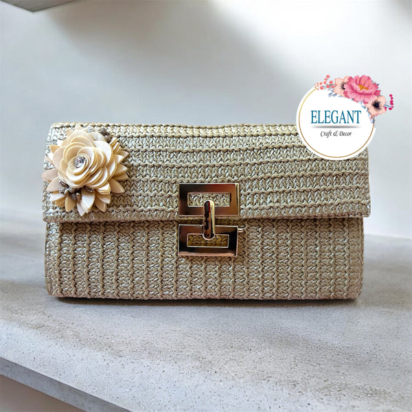 A classy woven clutch in a warm golden tone, featuring a textured finish, elegant metal clasp, and a delicate 3d floral embellishment for a chic, sophisticated look.