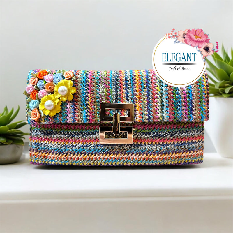 A vibrant woven clutch with multicolor patterns, a sleek metal clasp, and floral embellishments—perfect for a bold, stylish look.